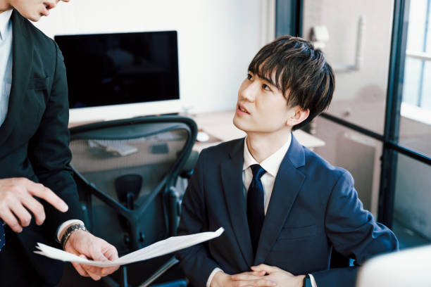 Two businessmen who work while consulting while looking at documents in the company Two businessmen who work while consulting while looking at documents in the company subordination stock pictures, royalty-free photos & images