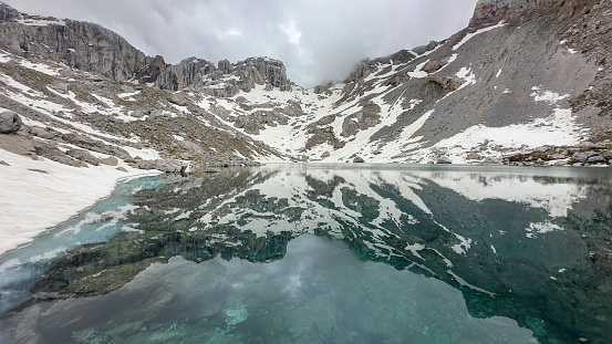 turquoise glacial lake on the top of high mountains and its reflection