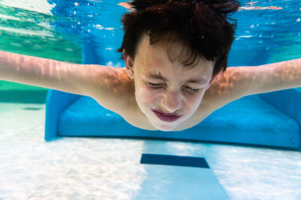 istock Cute boy swimming underwater in the pool 1493421754