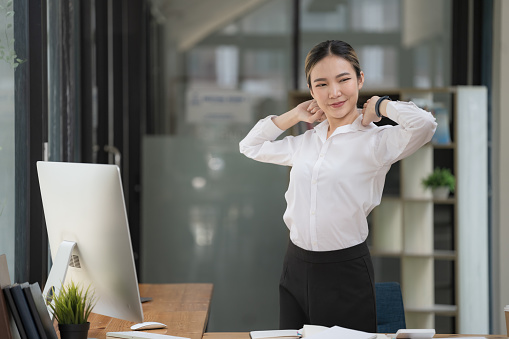 Businesswomen or working lady is stretch themselves or lazily for relaxation at their desk while doing their work in the office.