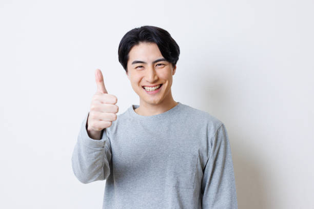Hombre japonés sonriendo y mostrando el gesto del pulgar hacia arriba - foto de stock