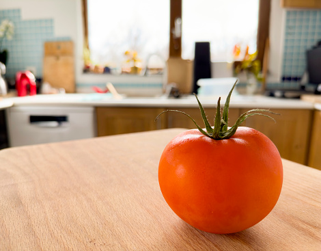 Beautiful red tomato on cutting board in kitchen