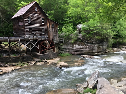 An aged water mill on a stony riverbank as the waters of a stream flow past