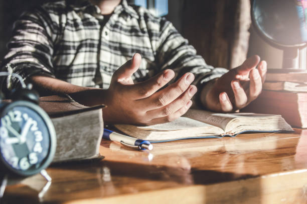 acerque las manos de los jóvenes leyendo la biblia y orando sobre una mesa de madera en casa por la mañana. concepto cristiano. - praying human hand worshipper wood fotografías e imágenes de stock