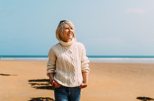 Mature woman walking on the beach at Dornoch in the Sutherland region of Scotland.