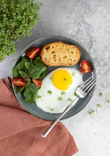 istock Fried eggs with green salad, cherry tomatoes and microgreens on a gray background. Breakfast concept. Top view. 1493442266