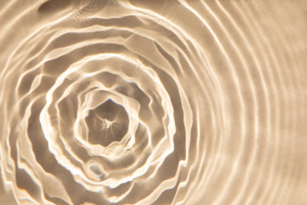 istock Abstract nature textured background, water waves with sun reflection. Clear water with bubbles and circles on beige background 1493443060