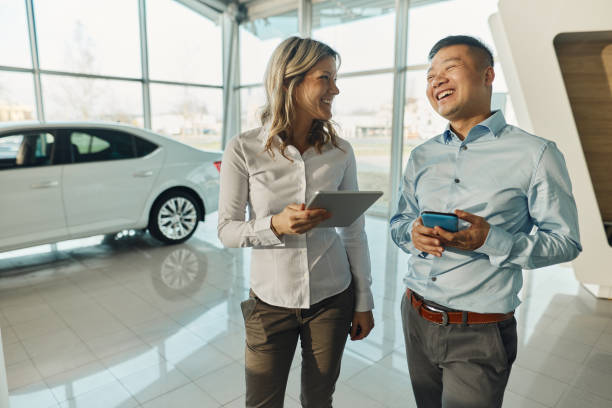 istock Happy business colleagues talking while using wireless technology in car showroom. 1493443365