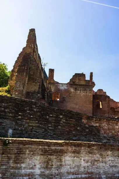 An outdoor view of a park featuring the ruins of a castle, including stone walls and towers in the background