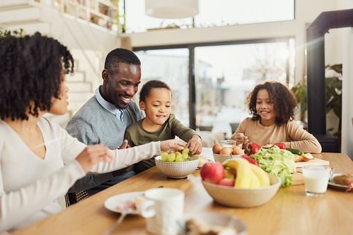 Happy African American family enjoying while having a meal in dining room.