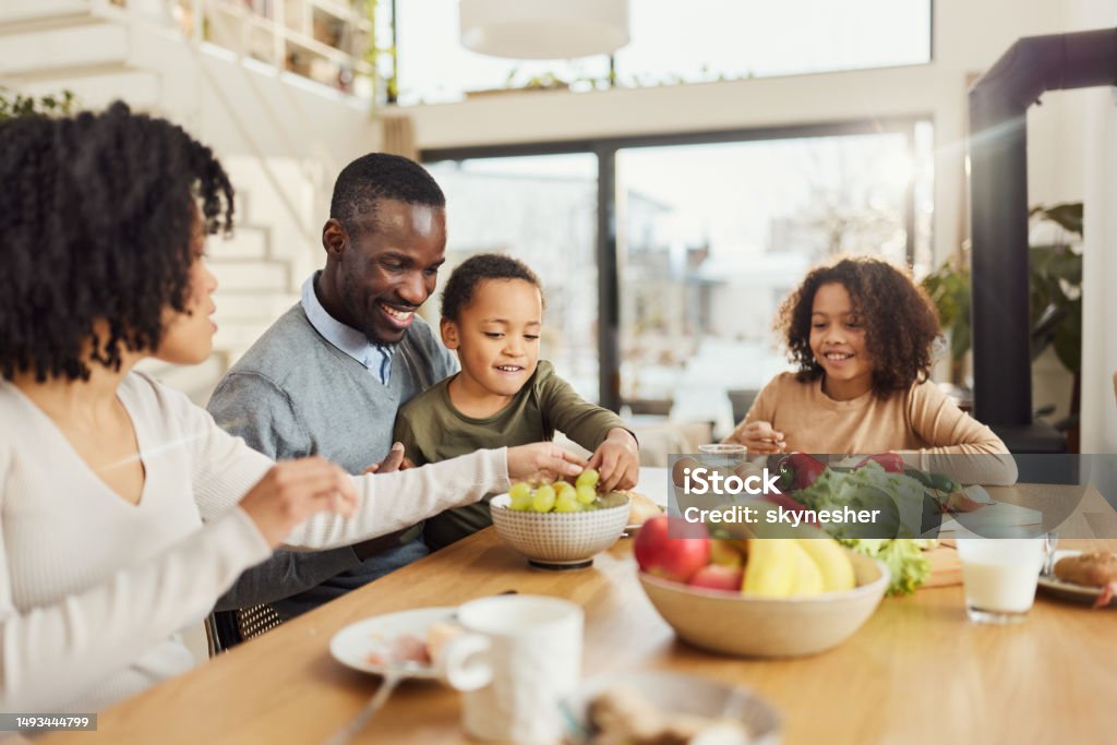 Happy Black Family Enjoying In A Meal At Dining Table Stock Photo