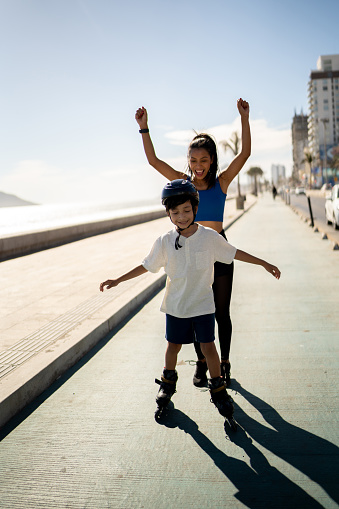 Boy learning to roller skating and mother's celebrating it on a beach coastline