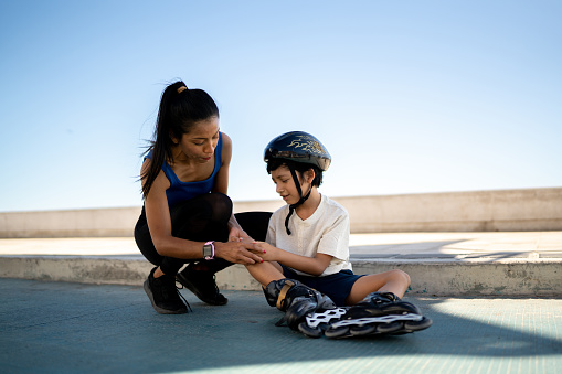 Mother helping son with his injury on the sidewalk