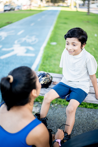 Mother helping son to put roller skates outdoors