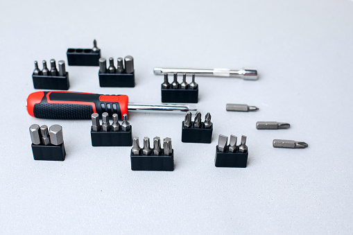 A set of working tools, screwdriver with bits for an answer on a gray concrete background. Top view