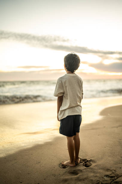 Boy looking away contemplating on the beach