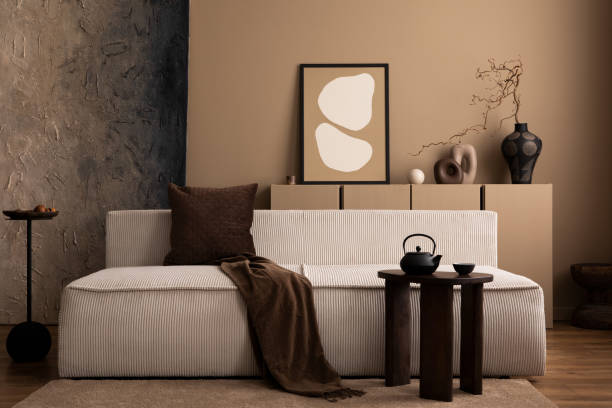 istock Interior design of creative living room interior with mock up poster frame, modular sofa, wooden coffee table, brown plaid, pillow, vase with branch and personal accessories. Home decor. Template. 1493446897