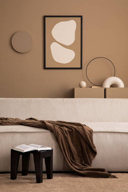 istock Warm and cozy living room interior with mock up poster frame, modular sofa, brown plaid, book, black stool, brown rug, sculpture and personal accessories. Home decor. Template. 1493447024