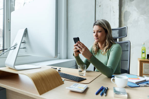 istock Young businesswoman using cell phone in the office. 1493447407