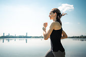 Woman with earbuds running in the park, side view portrait
