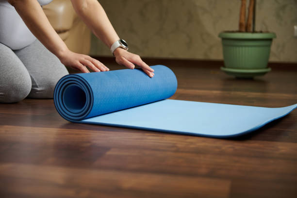 istock Close-up hands o pregnant woman rolling out a mat while practicing yoga, prenatal stretching, breathing exercises indoor 1493450953