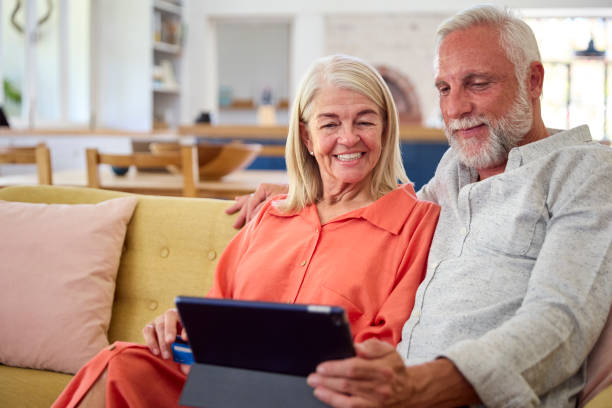 istock Retired Senior Couple At Home With Digital Tablet Making Purchase Or Booking Using Credit Card 1493453785