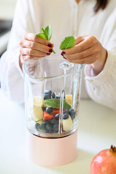 istock Crop woman putting mint leaves in blender 1493457863