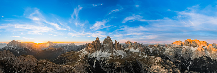 Rocky mountain peaks rise above deep shaded canyon at sunset. Mountain landscape of Tre Cime di Lavaredo in summer evening aerial view