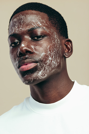 Man practicing a healthy skincare routine for his melanin skin, cleansing his face with a hydrating face wash. Young black man using a facial cleanser for a smooth and youthful-looking skin.