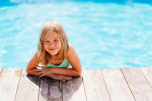 Cute and funny blonde teenage girlon the side of the pool. Safe rest with children by the water. travel and tourism. happy and carefree childhood