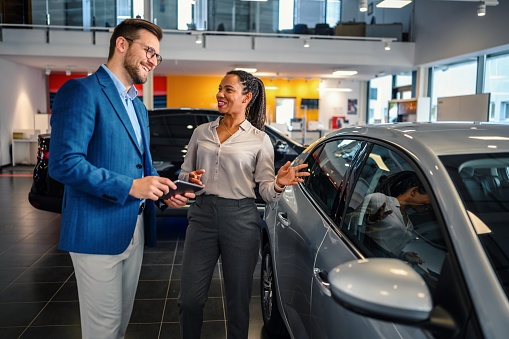 Saleswoman helping the male customer to choose a new car