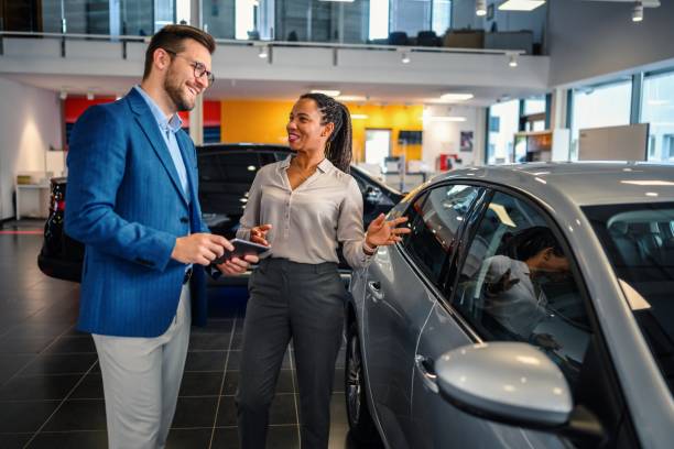 Salesman helping the male customer to choose a new car stock photo
