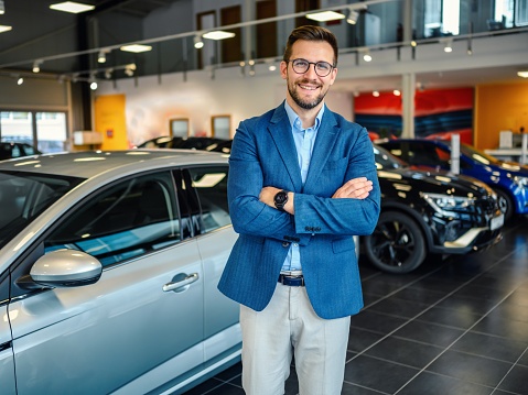 Portrait of a handsome male car salesman working in the showroom