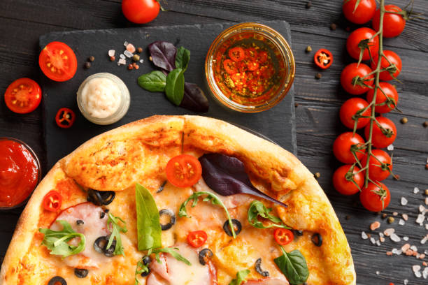 istock Pizza on a black stone dish on a dark wooden background, top view. 1493466465