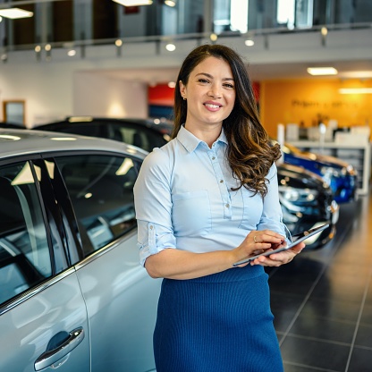 Portrait of a handsome female car saleswoman working in the showroom
