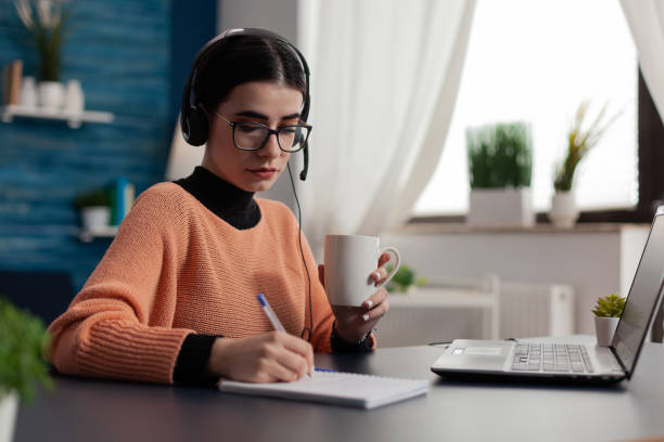 istock Student with headphones listening to online course and taking notes. 1493472890