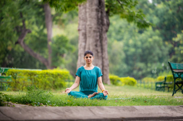 istock Young woman practicing yoga and meditation in lotus position at park 1493473454