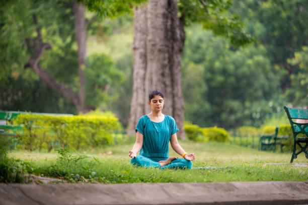 istock Young woman practicing yoga and meditation in lotus position at park 1493473455