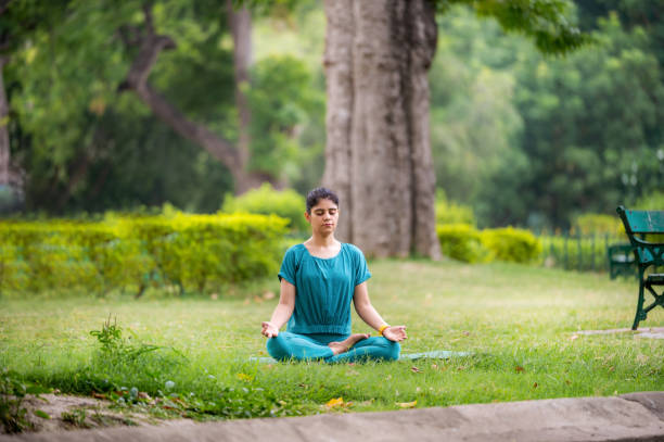 istock Young woman practicing yoga and meditation in lotus position at park 1493473457