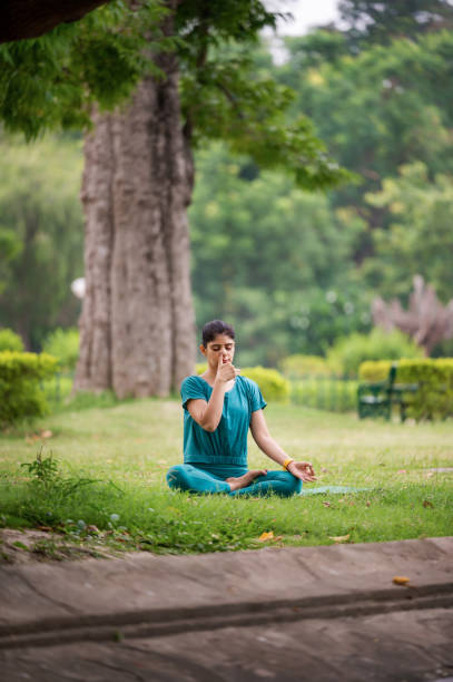 istock Young woman in practicing breathing exercise or Anulom Vilom at park 1493474260