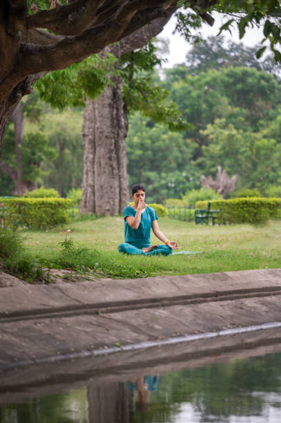 istock Young woman in practicing breathing exercise or Anulom Vilom at park 1493474419