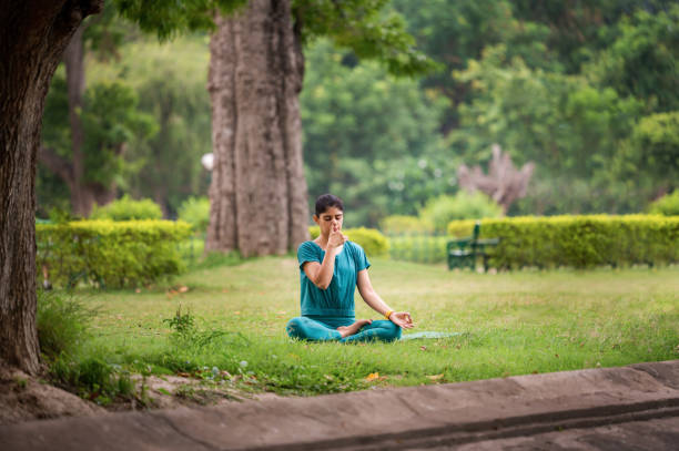 istock Young woman in practicing breathing exercise or Anulom Vilom at park 1493474455