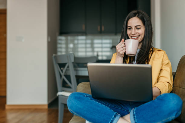 Young woman working from home on her couch in a relaxed pose stock photo