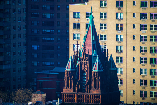 Jagged church spires rise sharply, cutting across the urban housing background of Manhattan's upper east side neighborhood. T