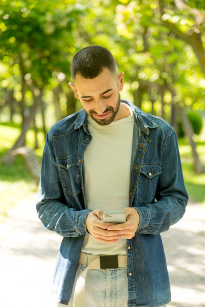 istock Young man texting on mobile phone in landscaped area 1493478547