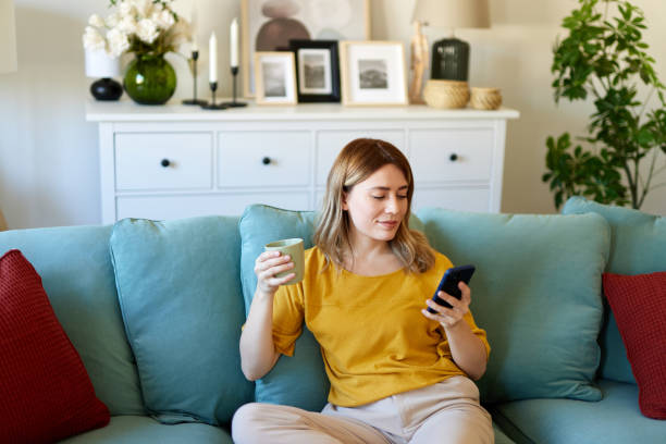 istock Woman using smartphone while drinking coffee at her home in the morning 1493478679