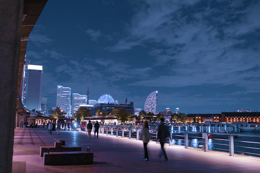 a photo with people lighting the path and buildings at one end and sea and skyscrapers at the end ，in minatomirai yokohama japan
