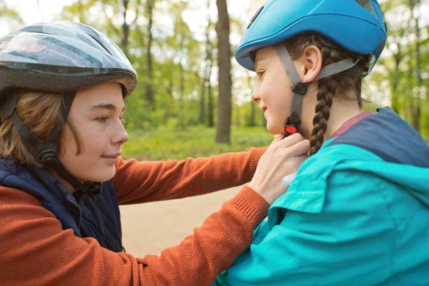 istock Boy helps his sister to put on helmet before roller-skating and riding scooter 1493480561