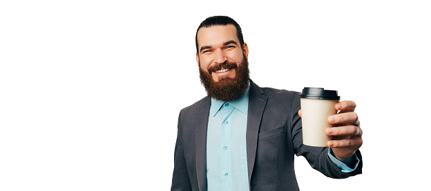 Banner size portrait of a bearded man handing a hot take away coffee to the camera.