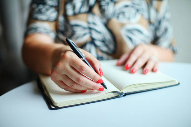 istock Close up of woman's hands writing in notepad placed 1493492672